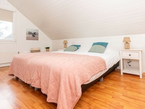 A bedroom with a bed, a nightstand, a lamp, a plant, and a window. - Holiday Home in Renesse With Swimming Pool (Renesse)