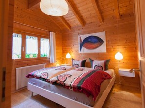 A wooden-paneled room with a bed, two bedside lamps, a radiator, and a window with curtains. - H&P Nature Adventure Village Stamsried (Stamsried)