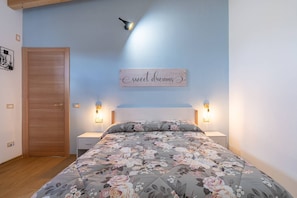 Et soveværelse med blomstret sengetæppe, en trædør og et skilt på væggen med teksten 'sweet dreams'.