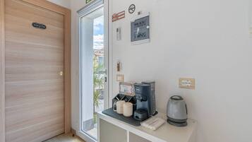 Ein Hotelzimmer mit Holztür, einem kleinen Tisch mit Kaffeemaschine, Tassen und einem Wasserkocher.