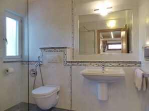 A bathroom with a toilet, a sink, a shower, and a mirror. - Holiday Apartment With 1 Bedroom (Caines)