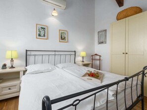 Ein Schlafzimmer mit einem Bett, zwei Nachttischen mit Lampen, einem Kleiderschrank und gerahmten Bildern an der Wand.