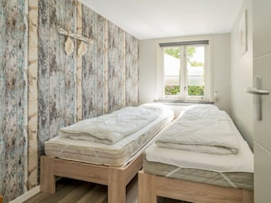 A room with two single beds, a wooden wall, a window with a view, and a white ceiling. - Holiday Home in Renesse With Swimming Pool (Renesse)