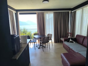 Een kamer met een tafel en stoelen, een bank, een open haard en uitzicht op het omliggende landschap.