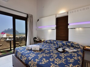 A modern hotel room with a large bed, a balcony with a view of the sea, and a wall-mounted air conditioning unit. - L"ea di Lavru - Apt 4 (Loiri Porto San Paolo)