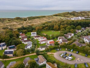 Ein Küstenwohngebiet mit Häusern, einem Parkplatz und Blick auf das Meer.