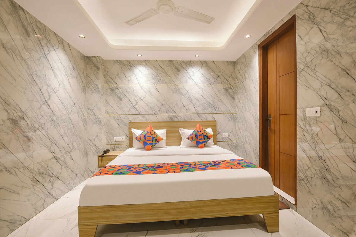 A hotel room with a bed, a nightstand, a wooden door, and marble walls.