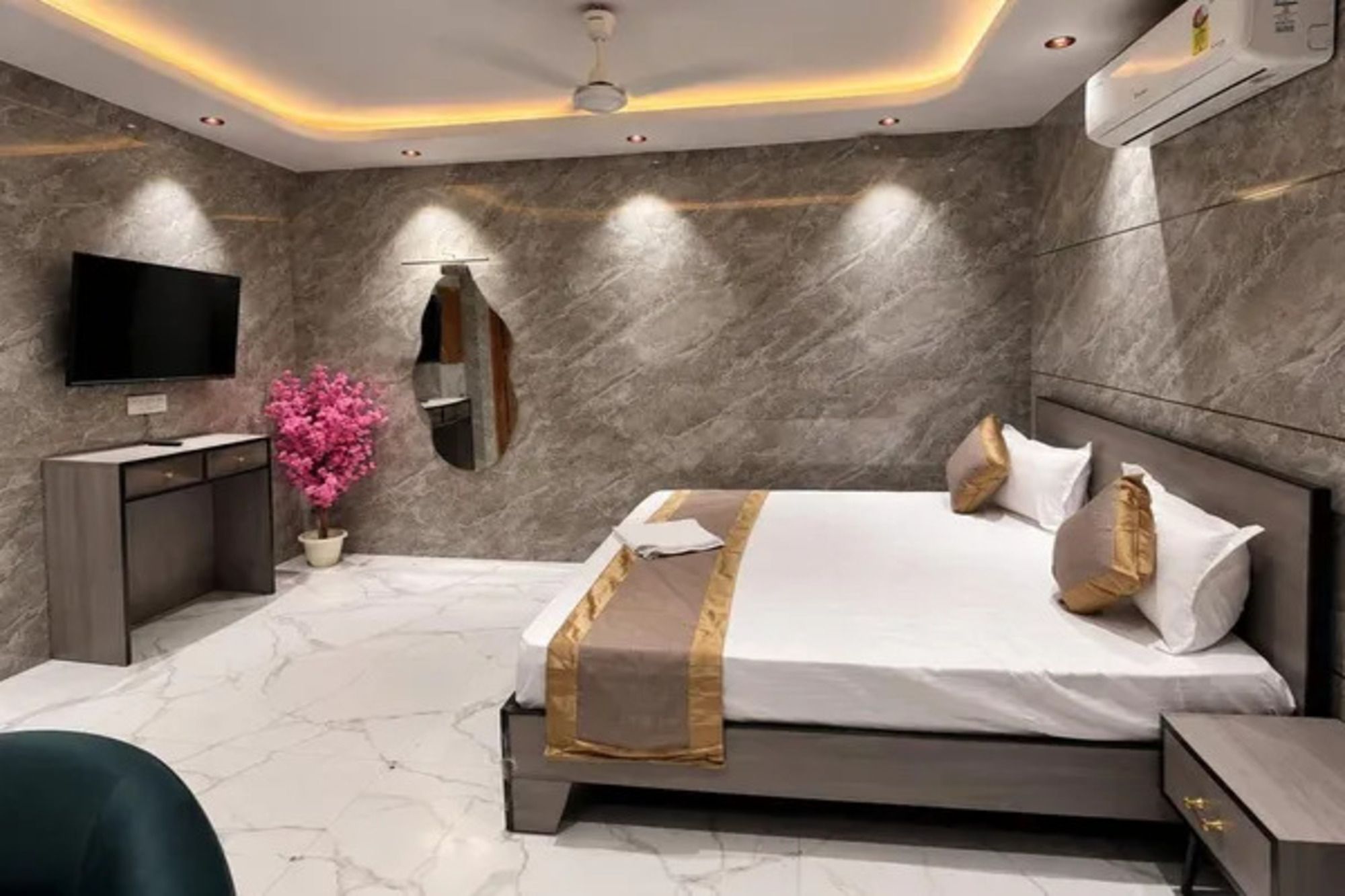 A modern bedroom with a large bed, bedside tables, a TV, and a mirror.