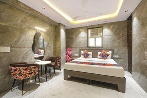 A modern bedroom with a large bed, a small table, two chairs, and a mirror on the wall. - FabHotel Abh Stay Home (New Delhi)