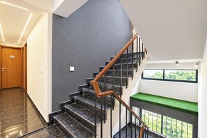 A modern interior with a staircase, a wooden door, and a window with a view of greenery. - FabHotel Abh Stay Home (New Delhi)