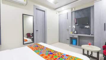 A hotel room with a bed, a mirror, a wardrobe, a television, and a small round table.