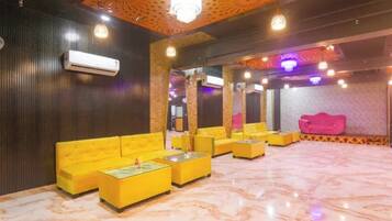 A lobby with yellow sofas, a marble floor, and a ceiling with patterned lighting.