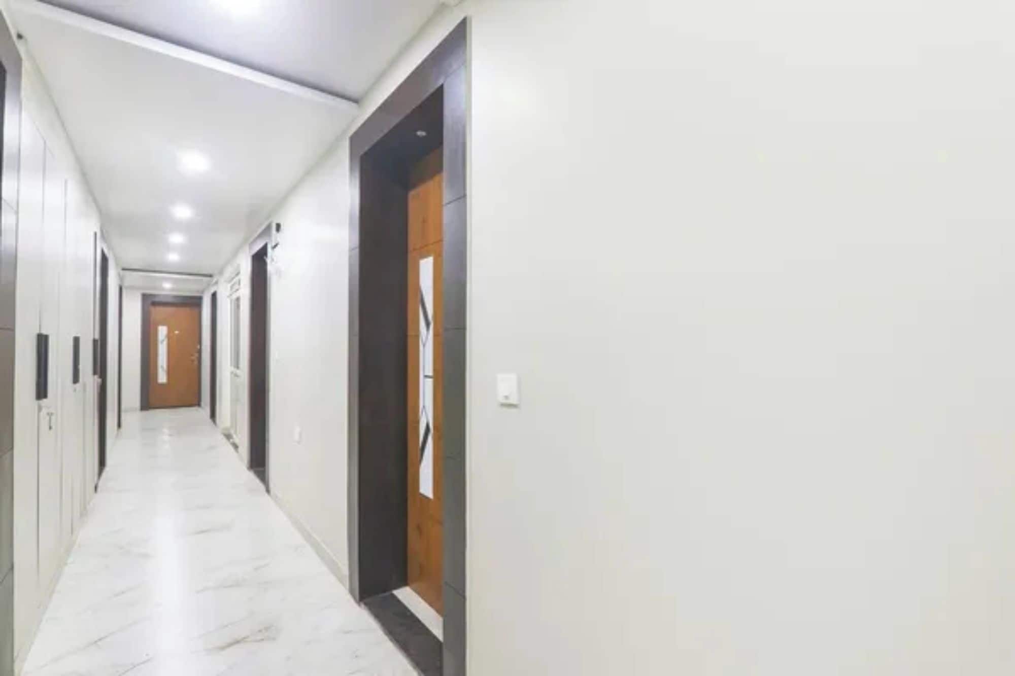 A long, narrow hallway with white walls and a marble floor.