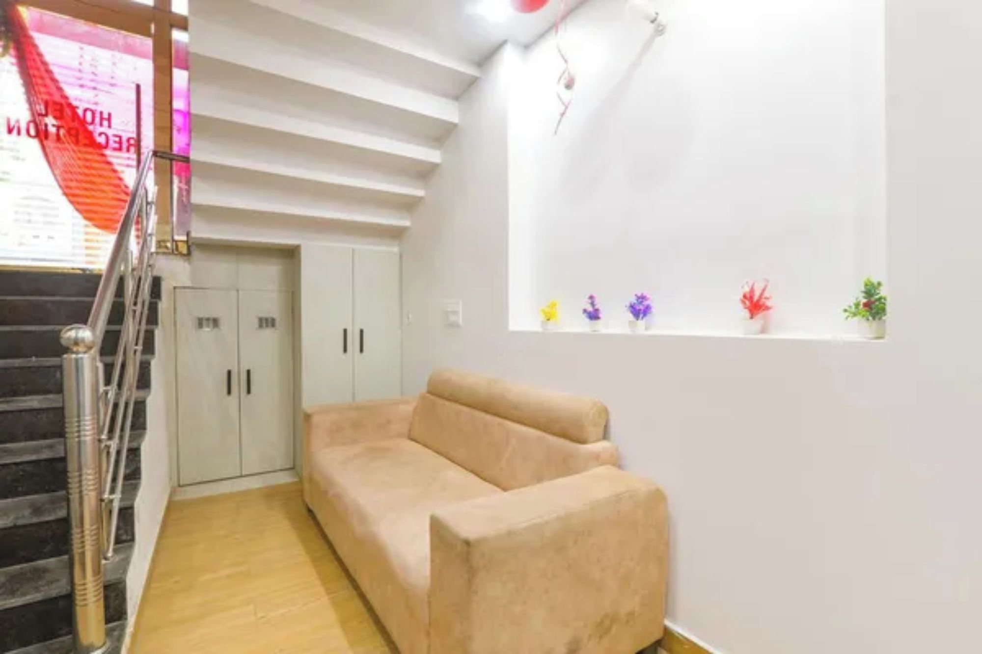 A room with a beige sofa, a staircase, and a window with small plants.