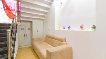 A room with a beige sofa, a staircase, and a window with small plants.