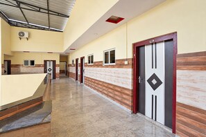 Un passadís amb portes, un ventilador al sostre i un terra d'azulejos.