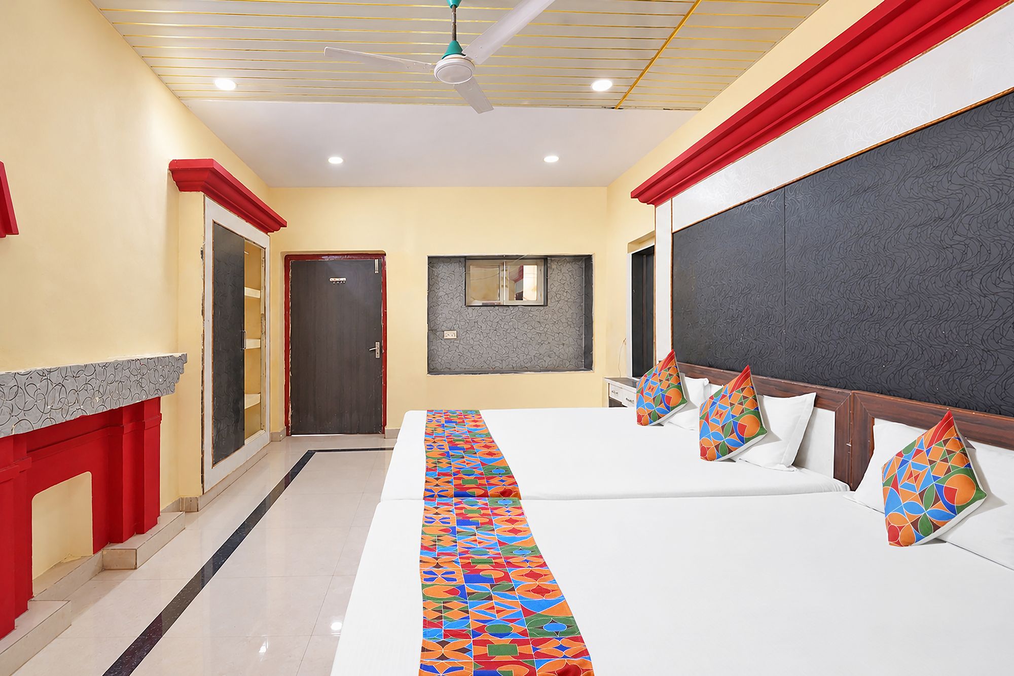 Une chambre d’hôtel avec un grand lit, un ventilateur de plafond, une porte et une fenêtre.