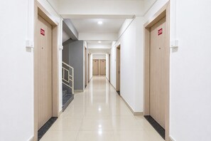 Un pasillo de hotel con puertas numeradas 209 y 206, una escalera y un suelo de baldosas impecable.