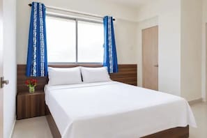 Quarto com cama, cortinas, mesa de cabeceira e porta.