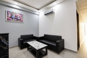 A modern waiting area with a marble coffee table, black leather sofas, and a colorful artwork on the wall. - FabHotel Grand Stay (New Delhi)