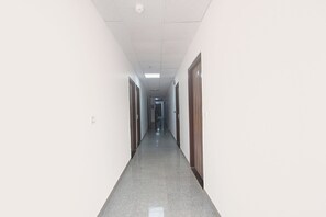 A long, narrow hallway with doors on both sides, leading to rooms.
