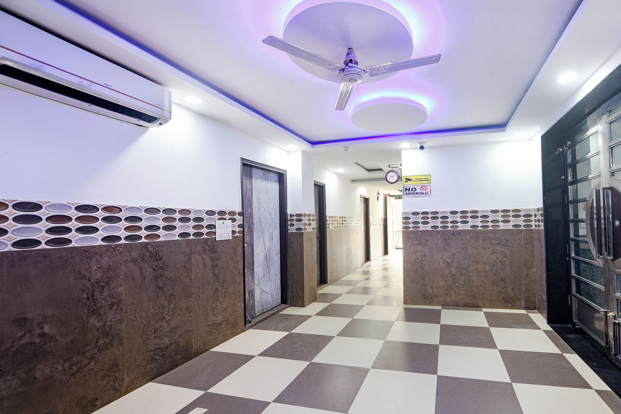 A hallway with a checkered floor, a ceiling fan, and a wall-mounted air conditioner.