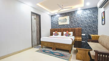 A bedroom with a bed, a wooden nightstand, a sofa, a ceiling fan, and a wall-mounted air conditioner.