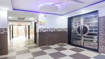 A hotel corridor with a checkered floor, a ceiling fan, and a door with a circular glass panel.