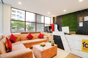Un vestíbul d'hotel modern amb un sofà, una recepció i una finestra gran.