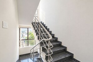 Una escala amb baranes metàl·liques que condueix a una plataforma amb una finestra que dona a una vista de la ciutat.