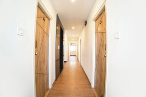 Un passadís amb portes de fusta i terra de fusta, que condueix a una habitació amb una finestra.