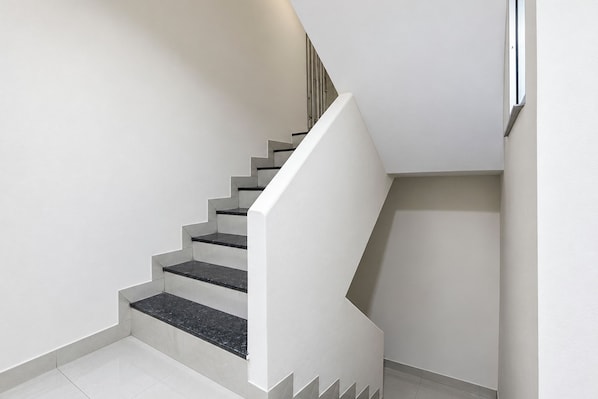A staircase with white walls and black steps.
