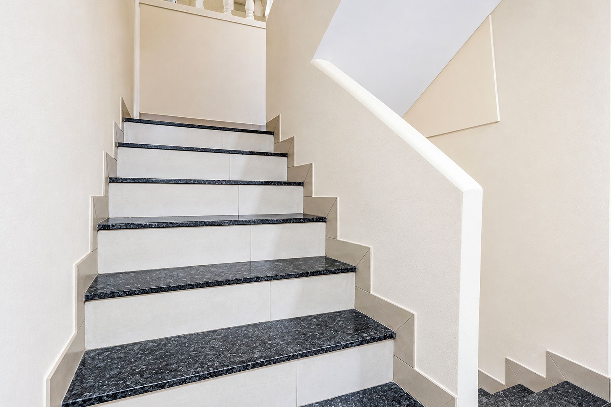 Eine Treppe mit weißen Wänden und schwarzen Marmorschritten.