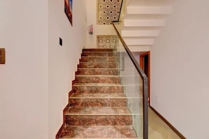 A staircase with a glass railing and patterned carpet. - FabHotel Livora Stays (Lucknow)