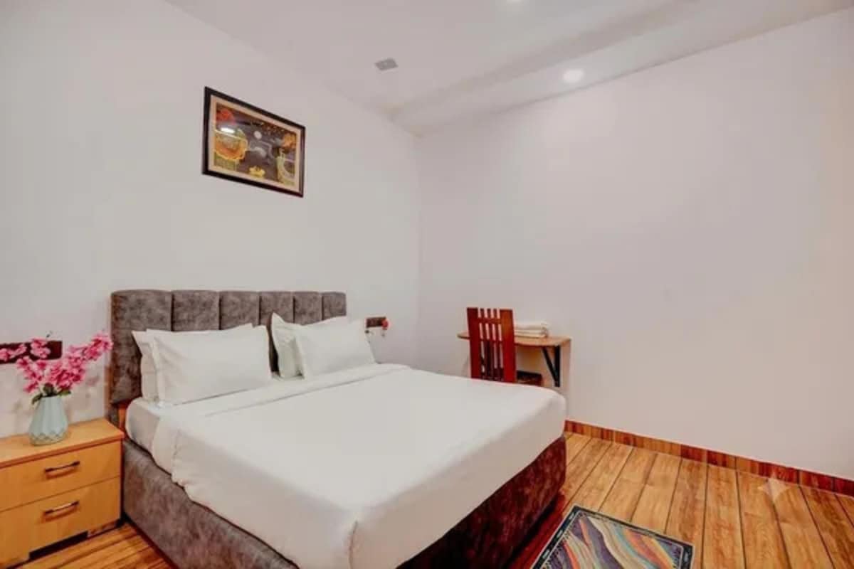 A bedroom with a bed, a nightstand, a chair, and a small table.