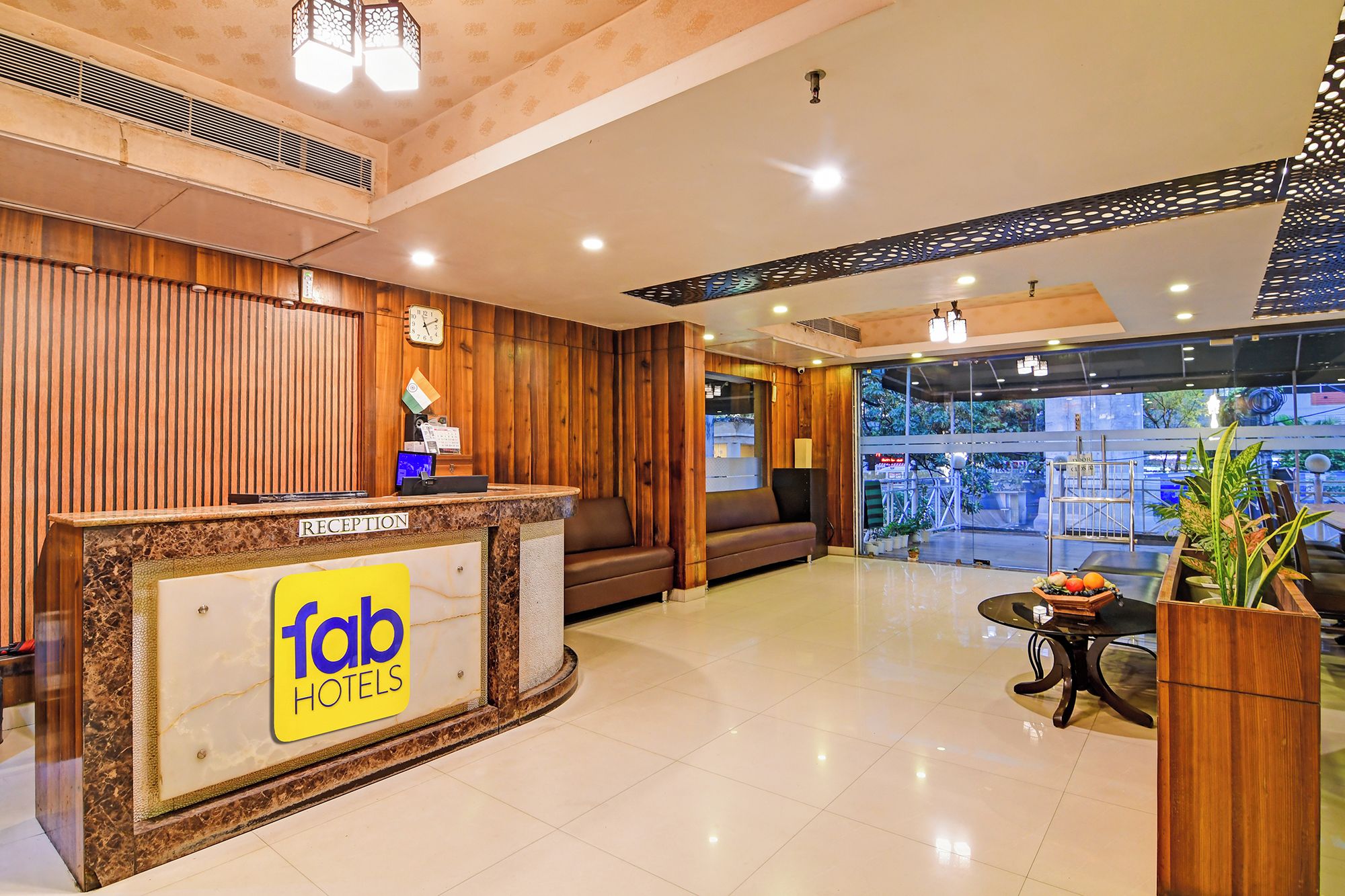 Uma área de recepção de hotel, com balcão, assentos e vista para o exterior.