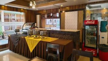 Un restaurante con zona de bar, refrigerador de Coca-Cola y mesas y sillas.