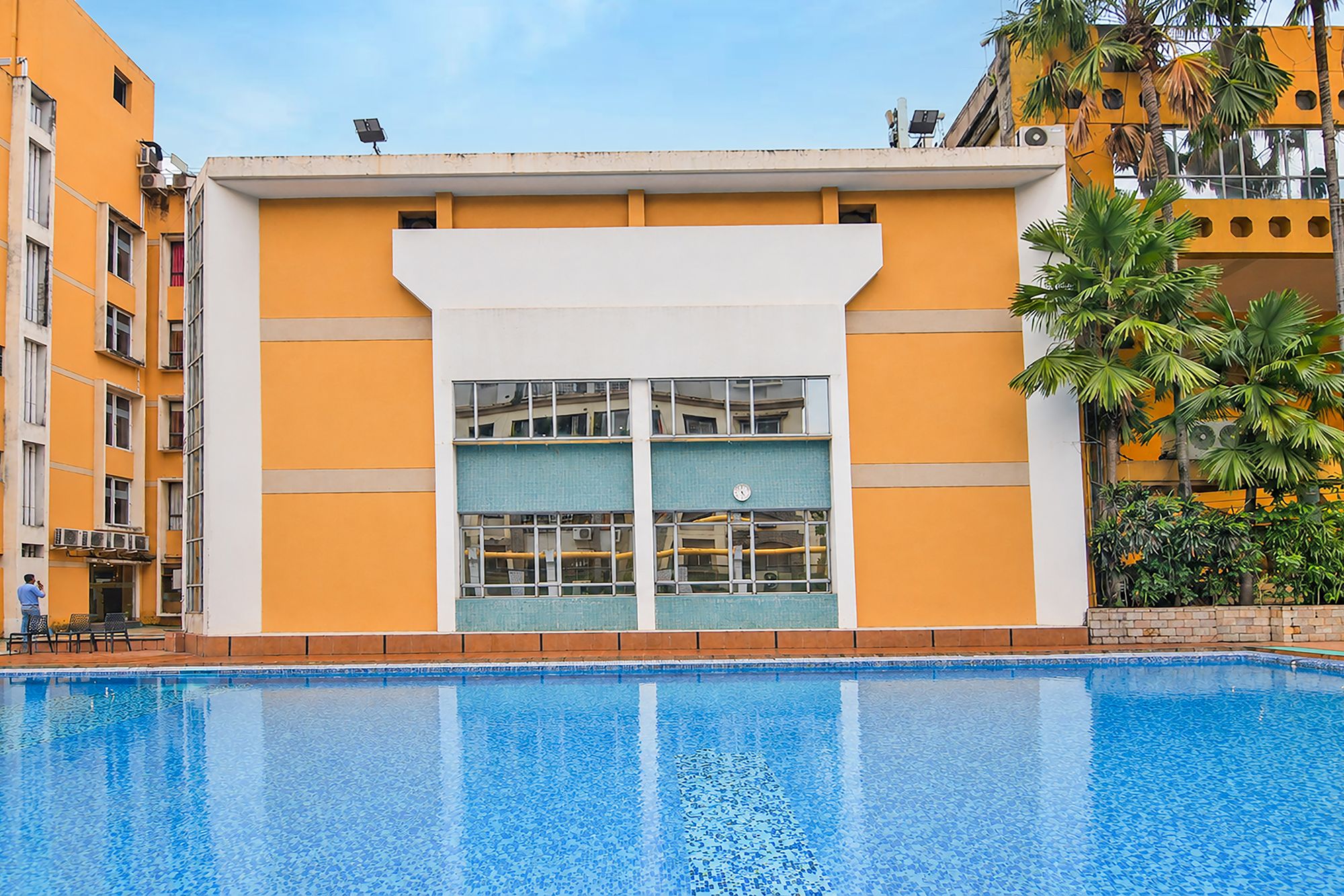 A building with a pool in front, featuring a large window with a view of the pool.