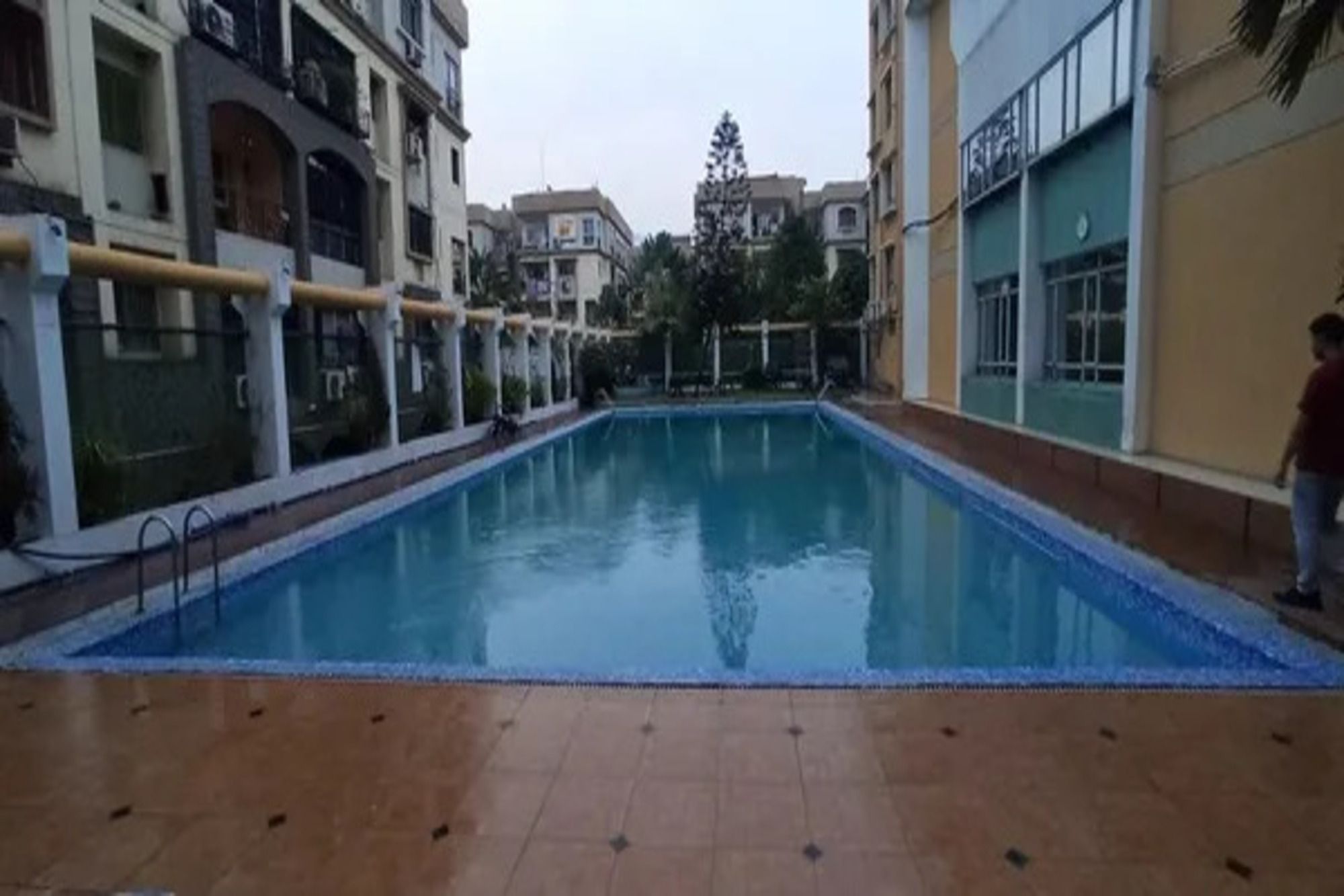 Una piscina con un bordeado de baldosas, rodeada de edificios con balcones y ventanas.