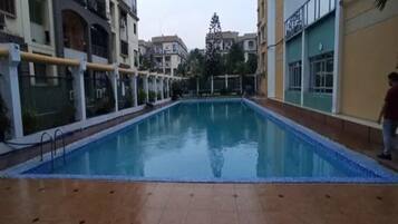 Una piscina con un bordeado de baldosas, rodeada de edificios con balcones y ventanas.