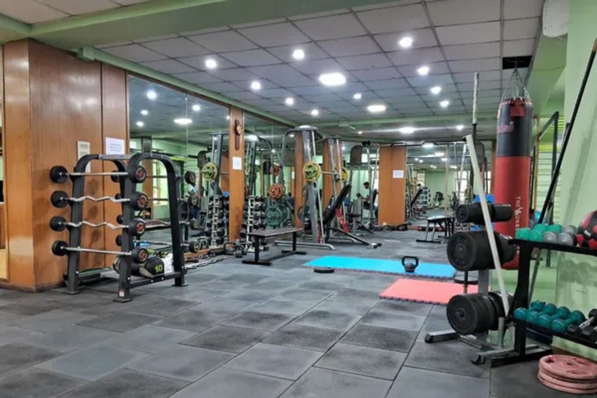 Un gimnasio con diversos equipos de ejercicio, incluyendo racks de pesas y pesas libres.