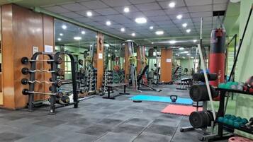Un gimnasio con diversos equipos de ejercicio, incluyendo racks de pesas y pesas libres.