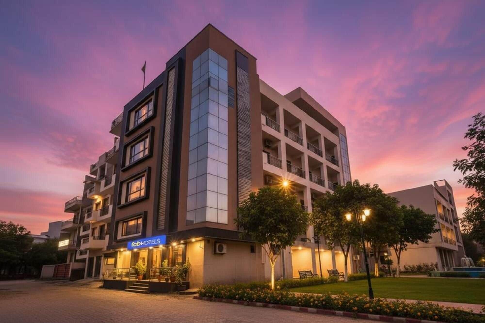Un hôtel à plusieurs étages au design moderne, doté d’une entrée imposante avec une enseigne et d’un jardin aménagé.