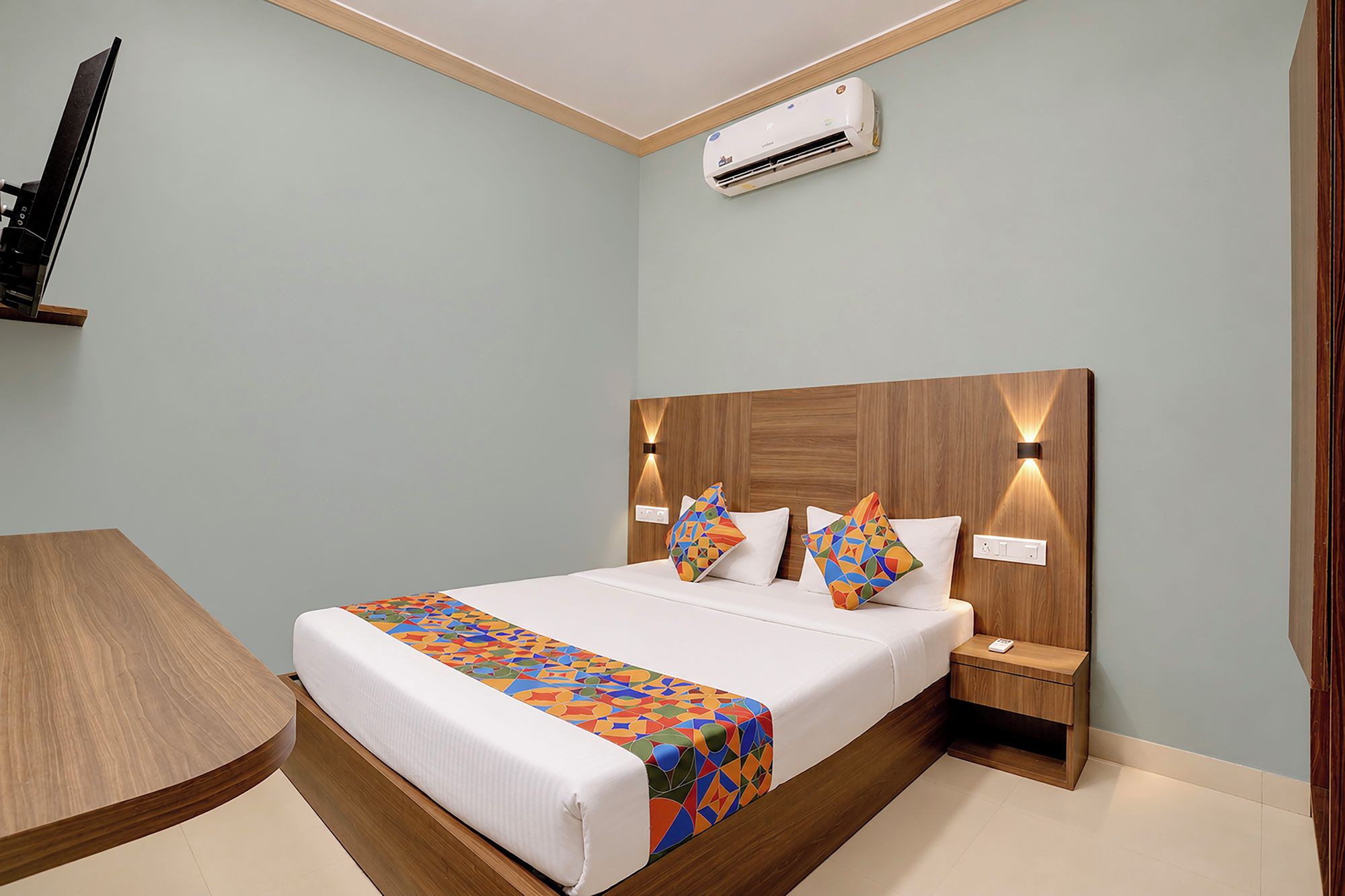 Una habitación de hotel con cama, mesita de noche y aire acondicionado.