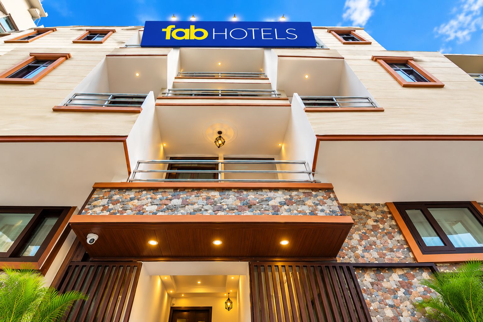 A hotel facade with a prominent 'fab HOTELS' sign, a stone-tiled entrance, and a modern balcony design.