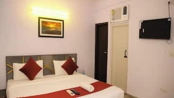 A hotel room with a bed, a TV mounted on the wall, and a door.