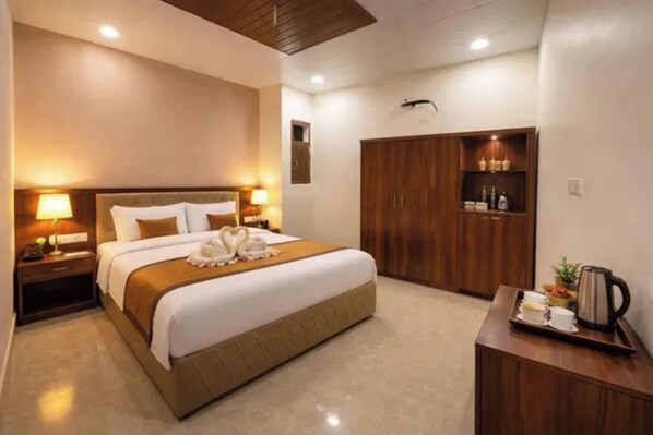 A hotel room with a bed, bedside lamps, a wardrobe, and a small table with a tray of breakfast items.
