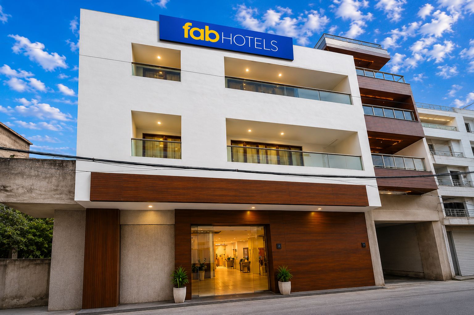 A modern hotel building with a prominent 'fab HOTELS' sign, multiple balconies, and a glass entrance.