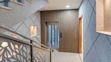 Un interior moderno con una escalera, una puerta con panel de madera vertical y un papel tapiz estampado.