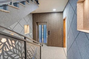 Un interior moderno con una escalera, una puerta con panel de madera vertical y un papel tapiz estampado.